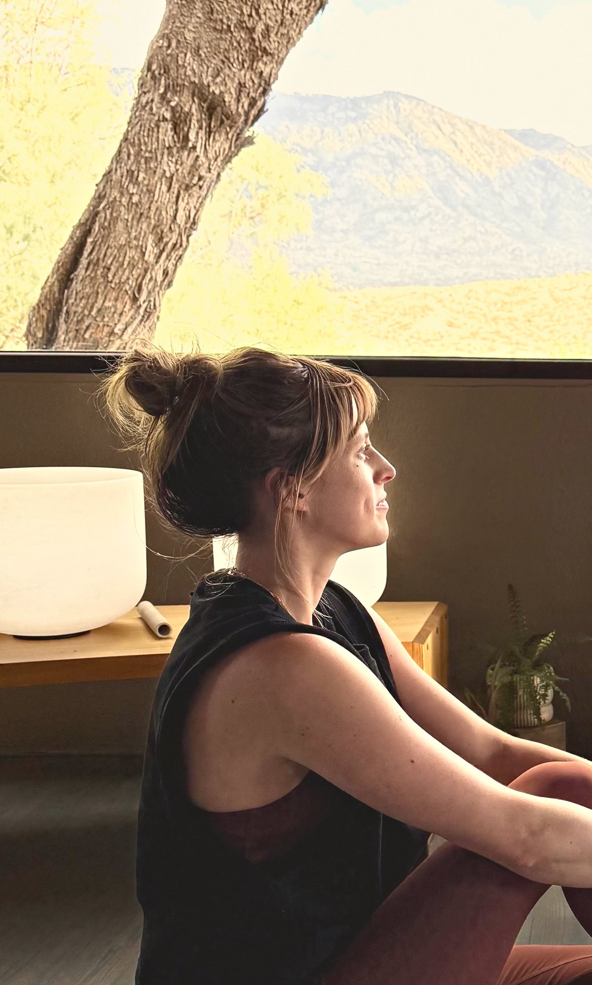 Mariah seated by a studio window, looking out toward the mountains