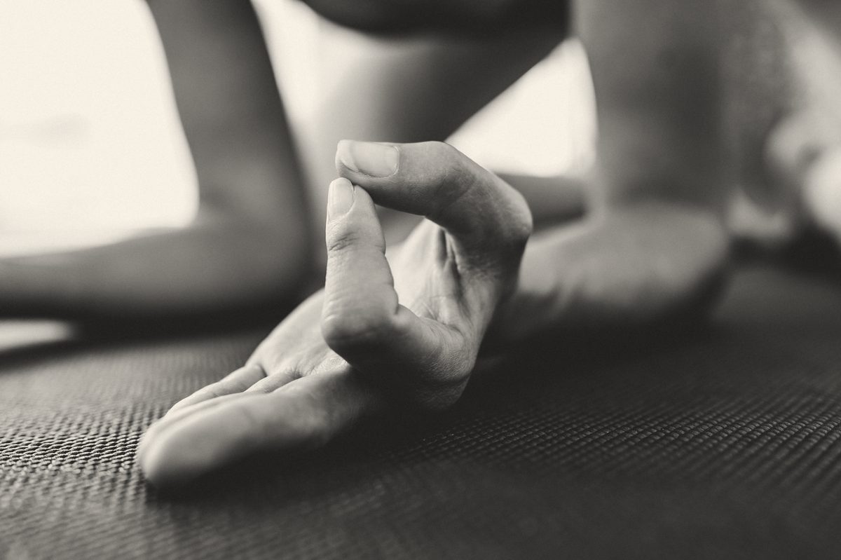 A hand resting on a mat in a seated pose